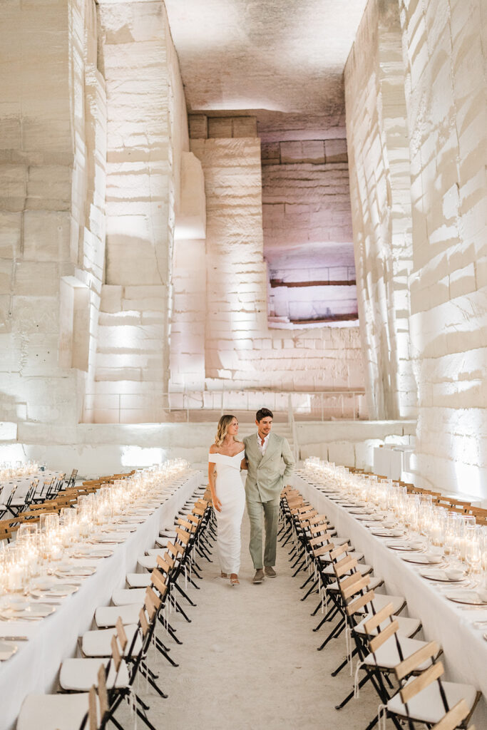 Un couple élégant marche dans un cadre unique, un espace épuré et romantique, parfait pour une cérémonie grandiose. Cet événement sur mesure, orchestré par By Mademoiselle C, illustre le luxe d'un mariage en Provence, Côte d'Azur et Corse, où chaque détail contribue à une célébration inoubliable, entouré de lumières scintillantes et d'une ambiance sophistiquée.