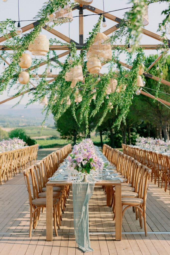 Une table élégamment dressée sous une structure en bois, entourée de verdure, évoque une célébration romantique et sophistiquée. Ce cadre idyllique, parfait pour un mariage sur mesure, met en avant une ambiance de luxe en Provence. Avec des fleurs délicates et des lumières suspendues, c'est un lieu exceptionnel pour un grand événement. Idéal pour une cérémonie de rêve dans un domaine privé.