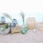 Décor élégant et romantique sur la plage, mettant en avant l'expertise de By Mademoiselle C en tant que Wedding Planner en Provence, Côte d'Azur & Corsica. Ce cadre unique, avec des vases en verre et des éléments naturels, évoque une ambiance de luxe pour une cérémonie de mariage sur mesure. Idéal pour une célébration grandiose, ce lieu privé offre une toile de fond parfaite pour un mariage de rêve, alliant sophistication et charme. Les détails