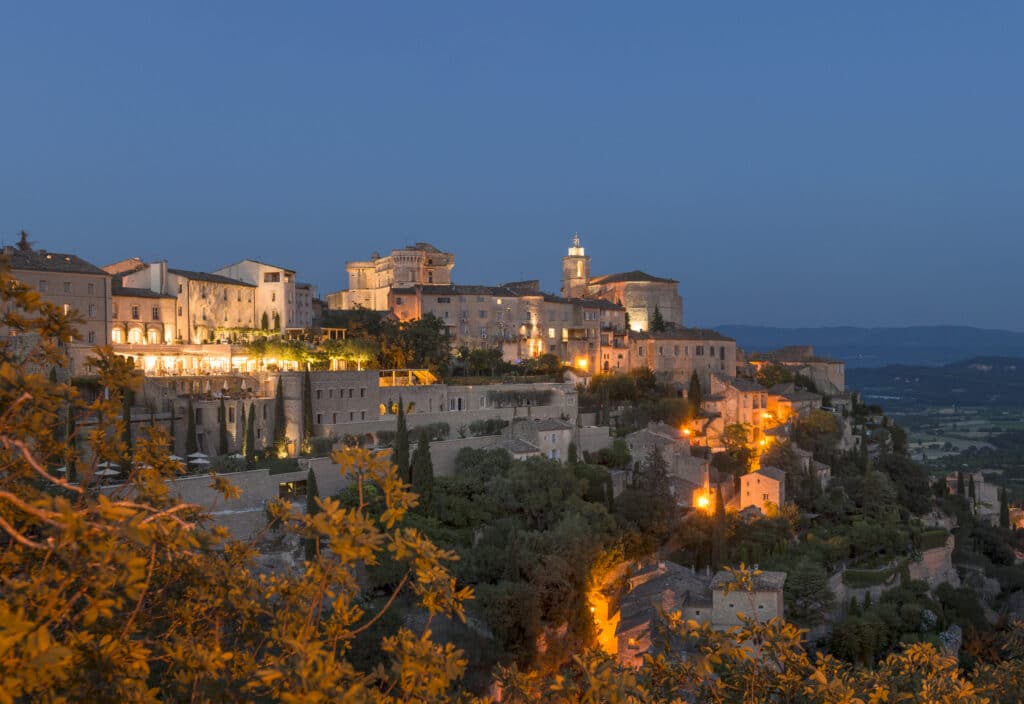 Une vue romantique sur un village provençal illuminé au crépuscule, parfait pour une cérémonie de mariage de luxe. Ce lieu exceptionnel, situé en Provence, est idéal pour une célébration grandiose, offrant des panoramas sur des vignobles et des jardins luxuriants. Avec son ambiance élégante et sophistiquée, il incarne l'essence d'un mariage sur mesure, où chaque détail est soigneusement organisé par By Mademoiselle C. Ce cadre enchanteur est