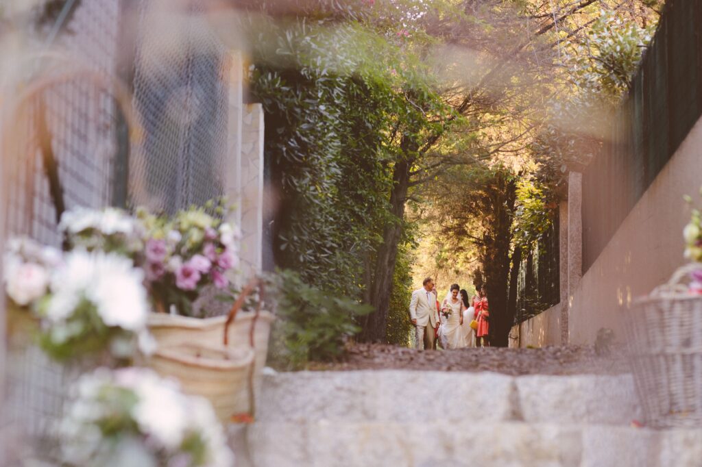 Une élégante cérémonie de mariage dans un domaine privé en Provence, où le couple, entouré de leurs proches, s'avance le long d'un chemin romantique, bordé de fleurs délicates. Cette image évoque une célébration grandiose et sur mesure, mettant en avant l'expertise de 'By Mademoiselle C' en tant que planificateur de mariage de luxe dans la Côte d'Azur et en Corse. L'atmosphère raffinée et sophistiquée, au