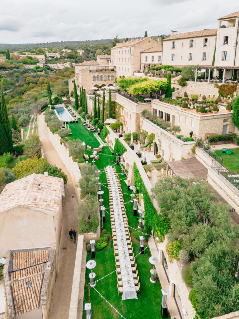 Une élégante réception de mariage dans un domaine privé en Provence, mettant en avant un long banquet sur une pelouse verdoyante, entouré de jardins raffinés. Ce cadre sophistiqué est parfait pour un mariage romantique et sur mesure, offrant un lieu exceptionnel pour une célébration grandiose. 'By Mademoiselle C' crée des événements uniques qui incarnent le luxe et le rêve dans le sud de la France.