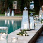 Éclairage romantique au bord de la piscine dans un domaine privé, créant une atmosphère élégante pour un mariage de luxe en Provence. Les lanternes scintillantes et les bougies ajoutent une touche sophistiquée à cette célébration sur mesure, idéale pour une cérémonie grandiose. Ce cadre enchanteur, entouré de verdure, est parfait pour un événement unique et mémorable, faisant de chaque instant un rêve devenu réalité. By Mademoiselle C transforme des lieux