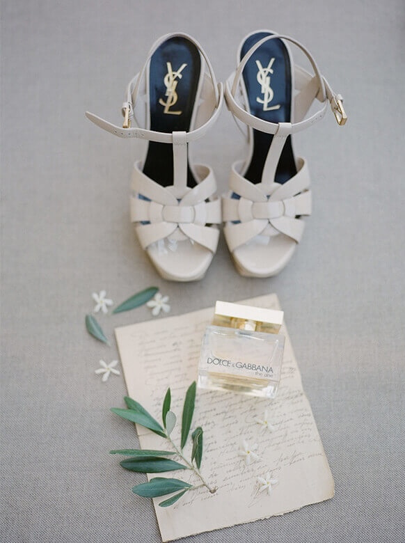 Chaussures élégantes et parfum délicat sur une toile raffinée, symbolisant le luxe d'un mariage sur mesure en Provence. Parfait pour une cérémonie romantique dans un domaine privé, chaque détail évoque une célébration grandiose. L’atmosphère sophistiquée promet une expérience unique pour un rêve de mariage inoubliable, orchestré par By Mademoiselle C.