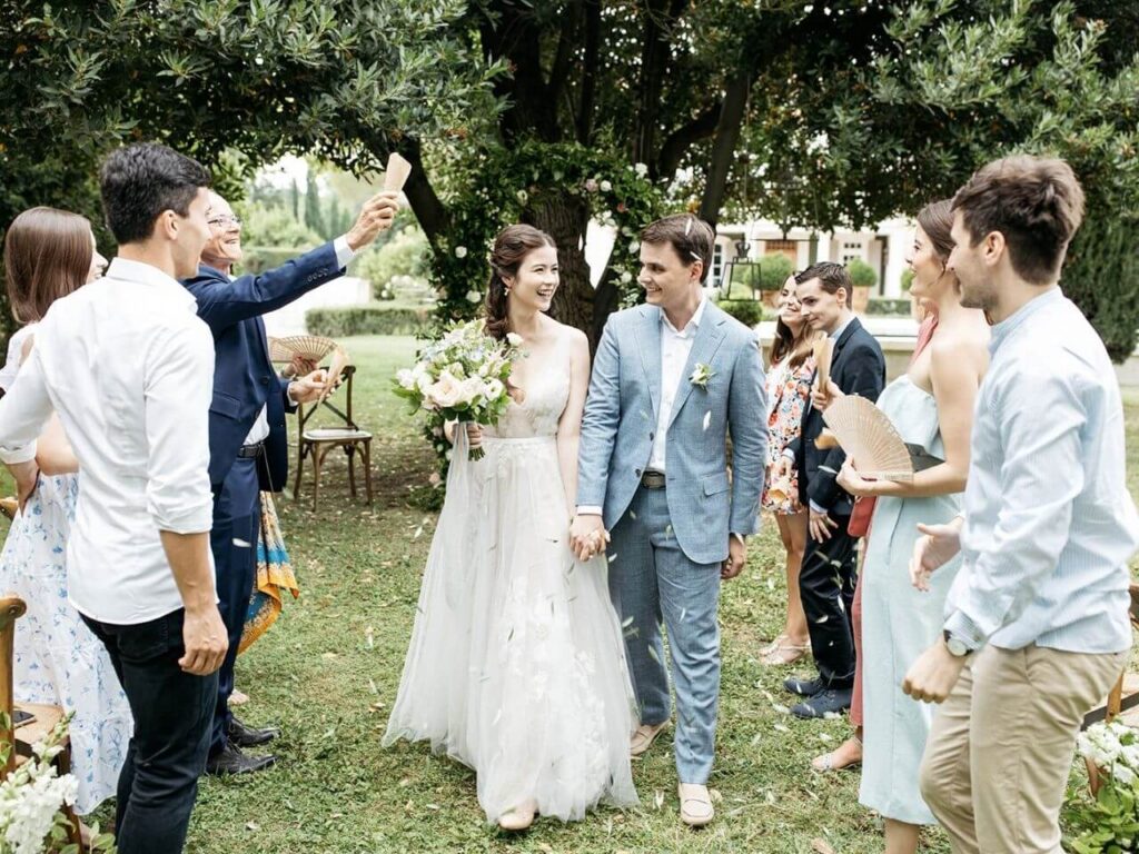 Un couple rayonnant célèbre leur mariage dans un jardin élégant, entouré de leurs proches, illustrant parfaitement une célébration romantique et unique. Cet événement sur mesure, organisé par By Mademoiselle C, incarne le luxe d'un mariage en Provence, avec des éléments de nature verdoyante et une ambiance sophistiquée. La cérémonie grandiose se déroule dans un domaine privé, offrant un cadre exceptionnel pour un mariage de rêve. Les invités, joyeux et accueillants, ajout