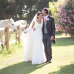 Un couple élégant se promène dans un jardin enchanteur, entouré de chevaux blancs et de fleurs colorées, illustrant la magie d'un mariage romantique. Cette scène évoque une célébration grandiose, parfaitement orchestrée par 'By Mademoiselle C', le planificateur de mariage de luxe en Provence, Côte d'Azur et Corse. Avec un cadre naturel idyllique et une attention méticuleuse aux détails, chaque moment de ce rêve de mariage devient une expérience unique