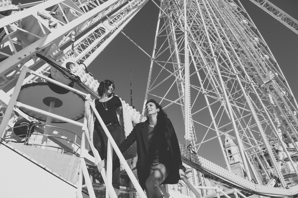 Une scène romantique et élégante capturant un couple souriant s'élevant vers la grande roue, symbolisant une célébration unique. En tant que wedding planner de luxe en Provence, Côte d'Azur et Corse, By Mademoiselle C crée des mariages sur mesure dans des lieux exceptionnels. Cette image évoque la magie d'un événement grandiose, parfait pour un mariage de rêve, entouré par l'atmosphère vivante et sophistiquée du sud de la France