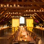 Un cadre élégant et romantique pour un mariage de luxe, mettant en valeur une grande cérémonie dans une magnifique salle de réception avec des poutres en bois et un éclairage doux. La table longiligne, soigneusement décorée, évoque une célébration sur mesure, idéale pour un événement unique en Provence, Côte d'Azur ou en Corse. Chaque détail, des bougies aux éléments floraux, contribue à créer une ambiance sophistiquée pour un rêve de mariage, entouré d'un