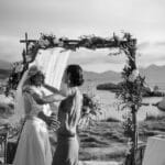 Célébration romantique d'un mariage de luxe au bord de la mer, mettant en avant une cérémonie en plein air dans un cadre naturel époustouflant. L'arche décorée de fleurs et le paysage de montagne en arrière-plan soulignent l'élégance et la sophistication de cet événement sur mesure. By Mademoiselle C, wedding planner en Provence, Côte d'Azur et Corse, crée des célébrations uniques et mémorables, transformant chaque moment en une expérience