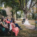 Cérémonie romantique en plein air, organisée par By Mademoiselle C, dans un cadre idyllique de Provence. Ce mariage sur mesure, niché dans un domaine privé, offre une atmosphère élégante et sophistiquée. Les invités, habillés avec goût, assistent à cet événement grandiose sous un majestueux arbre, tandis que le couple rayonne de bonheur. Un moment inoubliable pour une célébration unique, mettant en avant l'expertise de By M