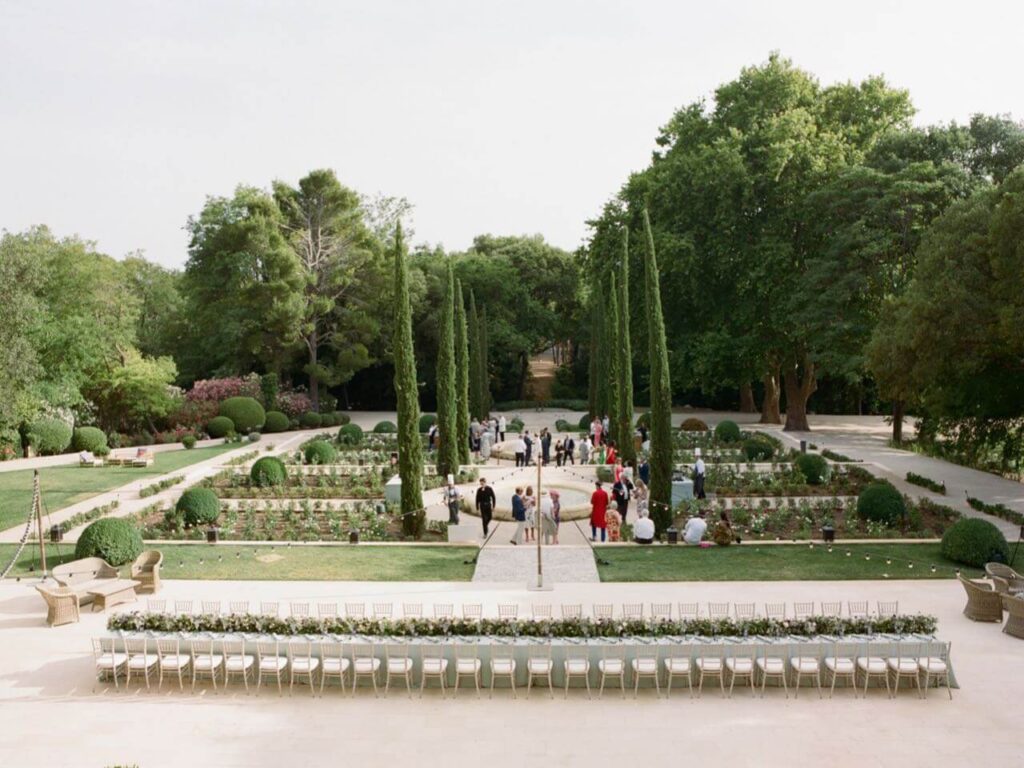 Un cadre romantique et élégant pour un mariage de luxe à Provence, Côte d'Azur et Corse. Ce jardin exquis, avec ses allées bordées de cyprès et ses parterres de fleurs soigneusement entretenus, est l'endroit idéal pour une cérémonie grandiose. La disposition sur mesure des chaises témoigne de l'organisation bespoke de 'By Mademoiselle C', créant une atmosphère sophistiquée pour une célébration unique. Ce lieu exceptionnel, entouré de