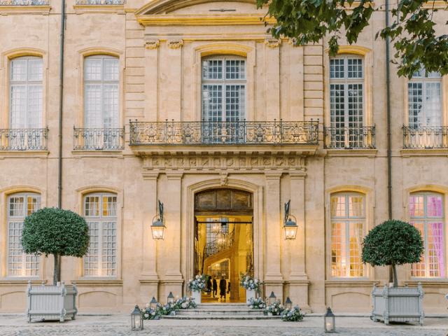 Superbe façade d'un hôtel de luxe, emblématique de la Provence, Côte d'Azur et Corse, idéale pour un mariage romantique. Cette propriété élégante, entourée de jardins soigneusement entretenus, incarne l'essence d'une célébration grandiose. Avec ses détails architecturaux raffinés, cet espace devient le cadre parfait pour une cérémonie exceptionnelle, organisée sur mesure par By Mademoiselle C. Offrez-vous une expérience de mariage unique dans un domaine privé, où