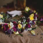 Couronne florale élégante mettant en valeur des roses jaunes et des fleurs d'un violet profond, symbolisant un mariage romantique et luxueux. Parfaite pour une organisation sur mesure dans des lieux exceptionnels en Provence, Côte d'Azur et Corse, cette pièce maîtresse évoque une célébration grandiose. Les détails raffinés de cette couronne illustrent l'expertise de By Mademoiselle C dans la création de mariages uniques et mémorables, transformant chaque événement