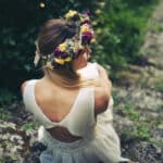 Une mariée élégante, coiffée d'une couronne de fleurs, se tient dans un cadre verdoyant, symbolisant la magie d'un mariage romantique. Cette image évoque l'expertise de By Mademoiselle C en tant que wedding planner en Provence, Côte d'Azur et Corse, spécialisée dans l'organisation de célébrations de luxe. Le décor naturel, typique des événements sur mesure, met en avant des éléments de sophistication et de charme, parfaits pour une cérémonie grand