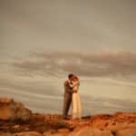 Un couple s'embrassant sur une plage rocheuse, incarnant l'essence d'un mariage de luxe en Provence, Côte d'Azur et Corse. Cette scène romantique évoque une cérémonie grandiose, avec un décor naturel époustouflant. L'atmosphère élégante et sophistiquée souligne l'expertise de By Mademoiselle C dans l'organisation de mariages sur mesure. Chaque détail de cet événement unique est pensé pour offrir une célébration inoubliable,