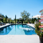 Une luxueuse piscine entourée de chaises longues élégantes et de verdure, idéale pour un mariage romantique dans un domaine privé en Provence. Ce cadre sophistiqué représente un lieu exceptionnel pour une célébration grandiose, où chaque détail est soigneusement organisé par By Mademoiselle C. Offrant une atmosphère de rêve, cet espace est parfait pour une cérémonie sur mesure, entourée de paysages enchanteurs, créant ainsi un événement unique et mémorable sur la Côte d'