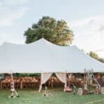 Tente élégante installée dans un jardin luxuriant pour un mariage romantique en Provence, mettant en avant une célébration grandiose. La disposition sur mesure des tables en bois et la décoration raffinée créent une atmosphère sophistiquée, idéale pour une cérémonie de luxe. Ce cadre exceptionnel, entouré de verdure, est parfait pour un événement unique, offrant une expérience de mariage sur mesure dans un domaine privé. 'By Mademoiselle C' excelle dans l'organisation de