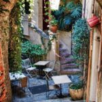 Un charmant coin de rue en Provence, enveloppé de verdure luxuriante, idéal pour un mariage romantique. Cet espace élégant, avec ses tables en fer forgé et ses escaliers en pierre, évoque une atmosphère sophistiquée, parfaite pour une célébration grandiose. 'By Mademoiselle C' excelle dans l'organisation de mariages sur mesure dans des lieux exceptionnels comme celui-ci, offrant une expérience unique pour un rêve de mariage inoubliable.