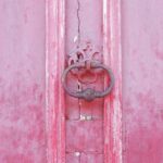 Une porte ancienne en bois rose, symbole d'une entrée vers un événement de luxe. Parfaite pour un mariage romantique, cette porte évoque l'élégance et la sophistication des cérémonies sur mesure organisées par By Mademoiselle C. Imaginez un grand événement dans un domaine privé en Provence, Côte d'Azur ou Corse, où chaque détail est conçu pour créer une célébration unique. Les couleurs douces et le charme d'un cadre pittoresque font de cet endroit le