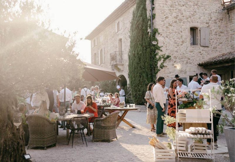 Un élégant mariage en plein air dans un domaine privé en Provence, où des invités savourent des moments précieux dans une atmosphère romantique. La lumière dorée du soleil met en valeur les détails raffinés d'une célébration sur mesure, avec des tables soigneusement dressées entourées de jardins luxuriants. Ce cadre exceptionnel, idéal pour un grand événement, témoigne de l'expertise de By Mademoiselle C en matière de planification de mariages de luxe, faisant de chaque instant