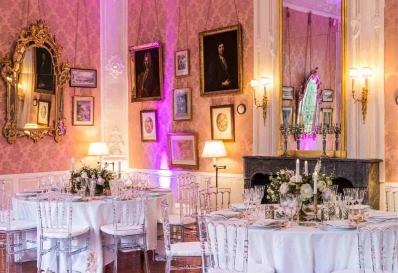 Une élégante salle de réception ornée de miroirs dorés et de décorations raffinées, parfaite pour un mariage de luxe en Provence. Les tables dressées avec soin, entourées de chaises transparentes, évoquent une atmosphère romantique et sophistiquée. Ce cadre unique, idéal pour une cérémonie grandiose, souligne l'expertise de By Mademoiselle C dans l'organisation de mariages sur mesure. Avec des éléments de décoration florale délicats, cette scène évo