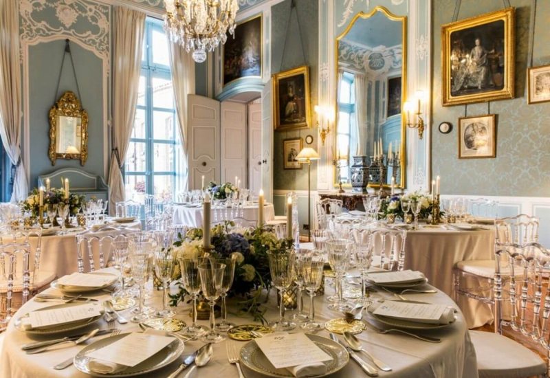 Une magnifique salle de réception pour un mariage romantique, mettant en valeur l'élégance d'une cérémonie grandiose. Les tables sont soigneusement dressées avec des assiettes raffinées et des verres étincelants, créant une ambiance sophistiquée. Les lustres dorés et les miroirs anciens ajoutent une touche de luxe, idéale pour un événement sur mesure dans un domaine privé en Provence. Ce cadre exceptionnel est parfait pour une célébration mémorable, où chaque détail