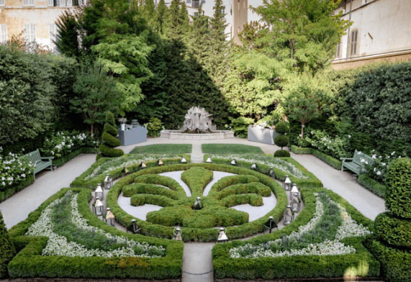 Jardin élégant et romantique, parfait pour une cérémonie de mariage sur mesure, organisé par By Mademoiselle C. Ce lieu exceptionnel, situé dans un domaine privé en Provence, évoque une célébration grandiose au milieu d'une nature luxuriante. Les parterres soigneusement entretenus et les lanternes délicates créent une atmosphère sophistiquée, idéale pour un mariage de rêve ou un événement unique. La beauté de ce jardin met en valeur l'expertise de notre