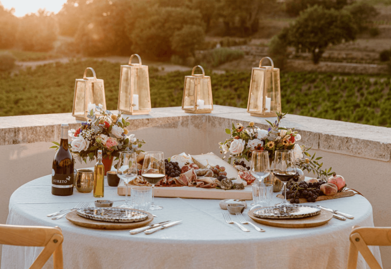 Une table élégamment dressée pour un grand mariage en Provence, entourée de vignes verdoyantes, évoque une atmosphère romantique et sophistiquée. Cette scène de fête met en avant un événement sur mesure, parfait pour une célébration luxueuse. Les lanternes dorées scintillent au coucher du soleil, ajoutant une touche de magie à ce domaine privé. Avec des plats raffinés et des vins exquis, ce cadre exceptionnel est idéal pour un mariage de rêve ou une unique