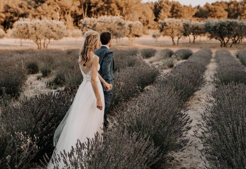 Un couple se promenant main dans la main dans un champ de lavande en Provence, représentant une scène idéale pour un mariage romantique. Ce cadre naturel évoque l'élégance d'une cérémonie grandiose, parfaitement orchestrée par By Mademoiselle C, le spécialiste des mariages de luxe en Provence, Côte d'Azur et Corse. Avec un décor de rêve et des lieux exceptionnels, chaque événement devient une célébration unique et sur mesure, créant des souvenirs inoubli