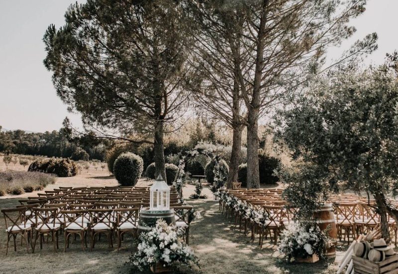 Un cadre romantique et élégant pour une cérémonie de mariage sur mesure, mettant en avant des chaises en bois disposées sous des arbres majestueux. Ce lieu exceptionnel, niché dans un domaine privé en Provence, évoque une atmosphère de luxe et de sophistication, parfaite pour une grande célébration. Les touches florales délicates ajoutent une note de charme à cet événement unique, idéal pour un rêve de mariage dans un cadre idyllique. By Mademoiselle C transforme chaque instant en