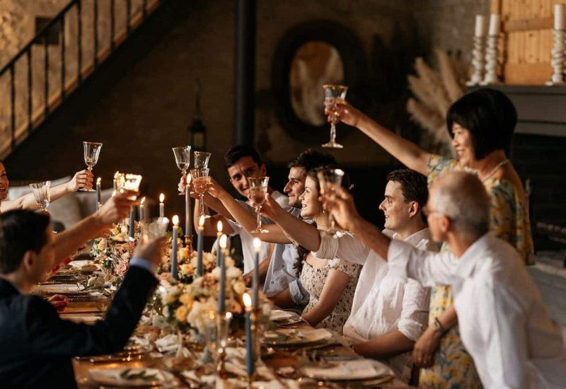 Célébration élégante entourée d'amis dans un cadre romantique, mettant en avant l'expertise de By Mademoiselle C en tant que wedding planner en Provence, Côte d'Azur et Corse. Cette scène de grand banquet, illuminée par des bougies et ornée de fleurs délicates, évoque une ambiance de luxe et de sophistication pour un mariage sur mesure. Chaque détail, des verres à champagne aux assiettes raffinées, souligne l'organisation d'un