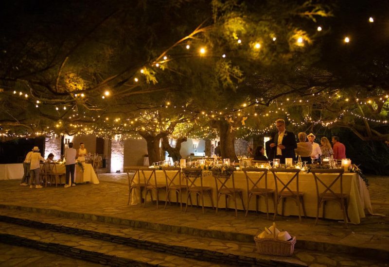 Une magnifique cérémonie de mariage en plein air, illuminée par des guirlandes lumineuses, offre une atmosphère romantique et élégante, parfaite pour un grand événement. Ce cadre exceptionnel, situé dans un domaine privé en Provence, invite à une célébration unique et sur mesure. Les tables soigneusement dressées, entourées d'arbres majestueux, créent un décor de rêve pour un mariage de luxe. Parfait pour un grand rassemblement, cet espace est idéal pour un