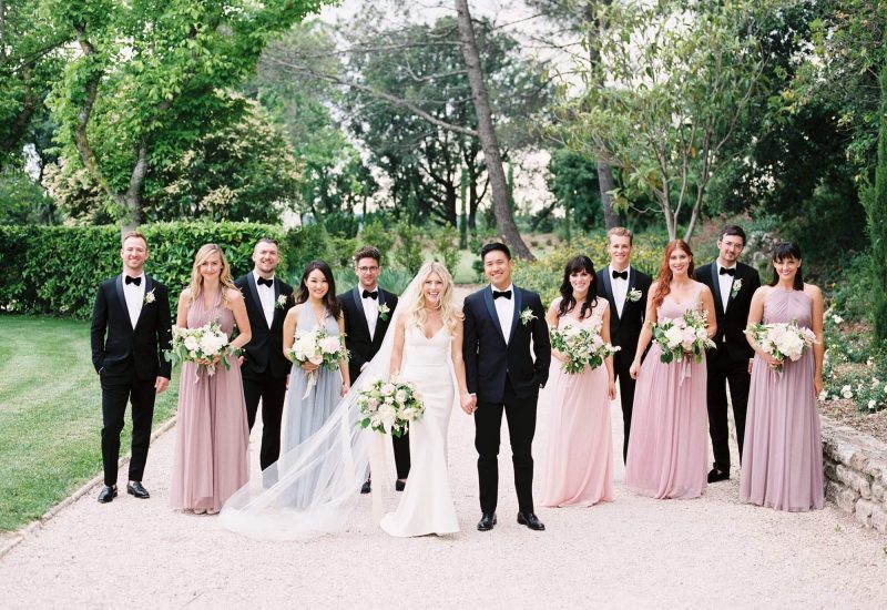 Un couple radieux entouré de leurs proches, célébrant un mariage de luxe dans un jardin élégant en Provence. Cette cérémonie romantique, orchestrée par By Mademoiselle C, incarne l'essence d'une fête sur mesure, avec des robes sophistiquées et des bouquets délicats, pour un événement unique dans un cadre enchanteur.