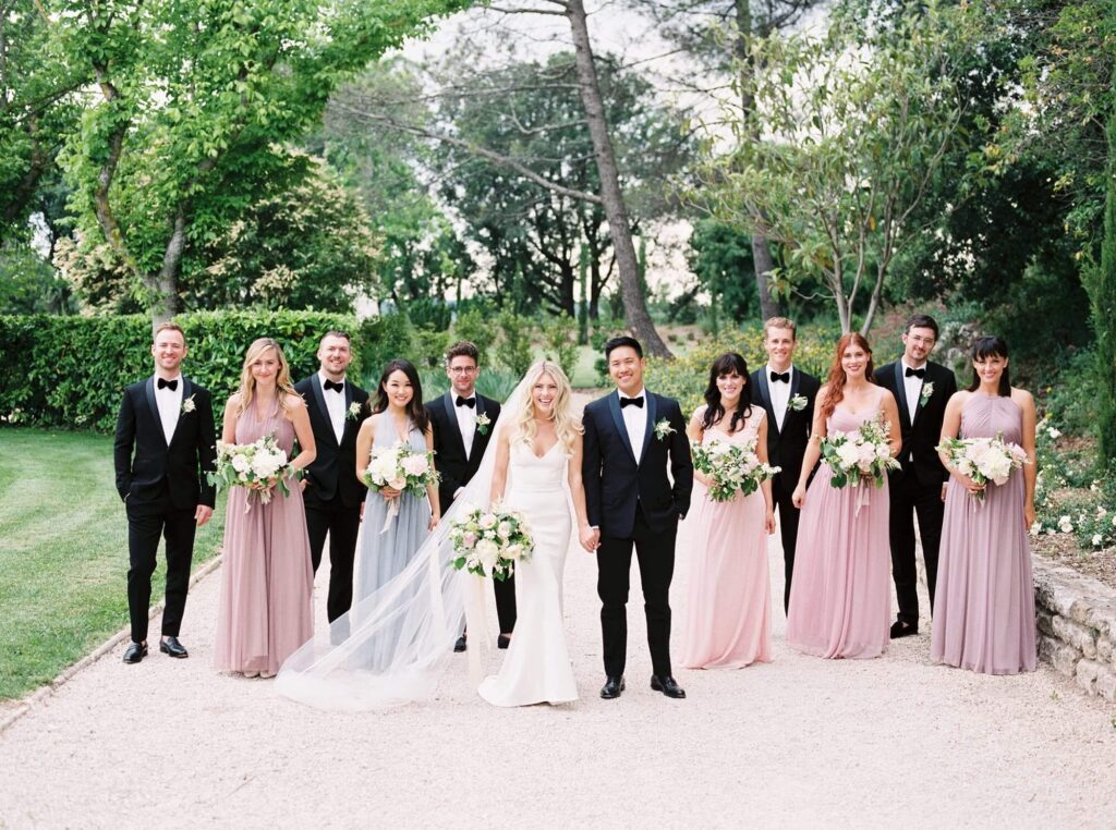 Un couple radieux entouré de leurs proches, célébrant un mariage de luxe dans un jardin élégant en Provence. Cette cérémonie romantique, orchestrée par By Mademoiselle C, incarne l'essence d'une fête sur mesure, avec des robes sophistiquées et des bouquets délicats, pour un événement unique dans un cadre enchanteur.