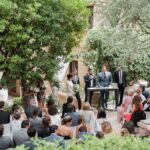 Cérémonie romantique en plein air dans un jardin élégant, mettant en valeur l'expertise de By Mademoiselle C en tant que wedding planner de luxe en Provence, Côte d'Azur et Corse. Les invités, habillés avec soin, assistent à un grand moment de célébration, entourés par un cadre verdoyant et des éléments de décoration sur mesure. Cette organisation de mariage sur un domaine privé incarne une expérience de mariage unique et sophistiquée, idéale pour un