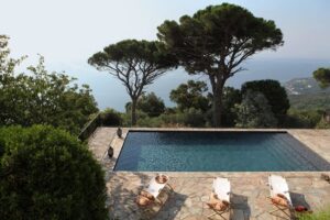 Vue panoramique sur une piscine élégante entourée de verdure, idéale pour un mariage romantique. Ce cadre enchanteur, situé dans un domaine privé de la Côte d'Azur, est parfait pour une célébration grandiose. Avec des chaises longues confortables et une atmosphère sophistiquée, cet espace est conçu pour un événement unique. By Mademoiselle C se spécialise dans l'organisation de mariages sur mesure, offrant des lieux d'exception pour un rêve de