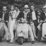 Élégante scène de mariage avec des invités joyeux sur des scooters vintage, illustrant une célébration unique et romantique. Ce moment capturé par 'By Mademoiselle C', expert en organisation de mariages de luxe en Provence, Côte d'Azur et Corse, met en avant l'atmosphère conviviale d'un grand événement. La touche personnalisée et le cadre pittoresque ajoutent une dimension magique à ce mariage sur mesure, idéal pour une grande cérémonie dans un