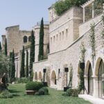 Un cadre élégant et romantique pour un mariage de luxe à By Mademoiselle C, mettant en avant un domaine privé en Provence. La façade en pierre de cet exceptionnel lieu de célébration s'intègre parfaitement dans le paysage verdoyant, créant une atmosphère sophistiquée pour une cérémonie grandiose. Ce cadre idyllique est idéal pour une organisation de mariage sur mesure, où chaque détail est pensé pour réaliser le rêve d'un événement unique et mémorable. Les jardins bien entretenus et