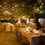 Un cadre romantique et élégant pour une célébration de mariage de luxe en Provence, Côte d'Azur et Corse, mettant en avant une organisation sur mesure par By Mademoiselle C. Les tables soigneusement dressées sous les arbres illuminés créent une atmosphère intime et sophistiquée, idéale pour un grand événement. Cet espace extérieur, entouré de verdure, est le lieu parfait pour un mariage exceptionnel, offrant un cadre unique pour une cérémonie de rêve. Découvrez l'art de