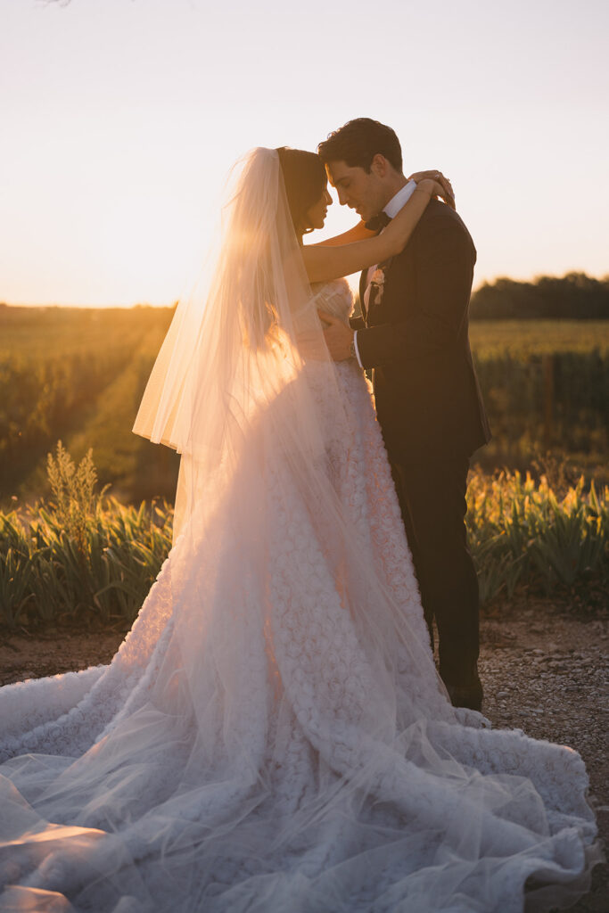 Un couple romantique se tient sous le coucher de soleil, entouré de vignes luxuriantes, illustrant une cérémonie de mariage de luxe. Cette scène évoque un événement sur mesure, parfait pour un grand mariage dans un domaine privé en Provence. L'atmosphère élégante et sophistiquée capture l'essence d'une célébration unique, faisant de ce moment un rêve devenu réalité.