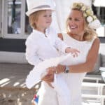 Une mère heureuse portant son enfant dans un cadre élégant et romantique, parfait pour un mariage de luxe en Provence, Côte d'Azur et Corse. Cette scène capture l'essence d'un événement sur mesure, où chaque détail est pensé pour créer une célébration grandiose. L'atmosphère dégage une sophistication unique, idéale pour un mariage de rêve ou une cérémonie exceptionnelle. Les vêtements blancs évoquent la pureté d'un mariage romantique, tandis que le décor environnant évoque un domaine