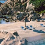 Plage isolée en Corse, idéale pour un mariage romantique, avec des transats élégants et des parasols, entourée de rochers majestueux et de végétation luxuriante. Un cadre parfait pour une célébration grandiose, offrant une expérience unique pour un événement sur mesure. By Mademoiselle C, expert en organisation de mariages de luxe, crée des souvenirs inoubliables dans des lieux d'exception en Provence, Côte d'Azur et Corse.