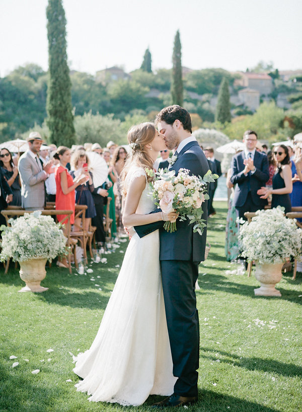 Un couple s'embrassant lors d'une cérémonie romantique en plein air, entouré de magnifiques jardins en Provence. Ce mariage de luxe, orchestré par 'By Mademoiselle C', illustre l'art de créer des événements uniques dans des lieux d'exception. Le cadre élégant et les invités ravis témoignent d'une célébration sur mesure, parfaite pour un rêve devenu réalité.