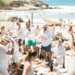 Une célébration luxueuse sur la plage en Provence, Côte d'Azur, mettant en valeur une ambiance romantique et élégante. Ce mariage sur la plage, organisé par By Mademoiselle C, incarne le rêve d'une cérémonie sur mesure, entourée par des amis joyeux. Les invités, habillés en blanc, profitent d'un cadre idyllique, avec des parasols et des chaises longues en arrière-plan, créant une atmosphère de grand événement. Chaque détail